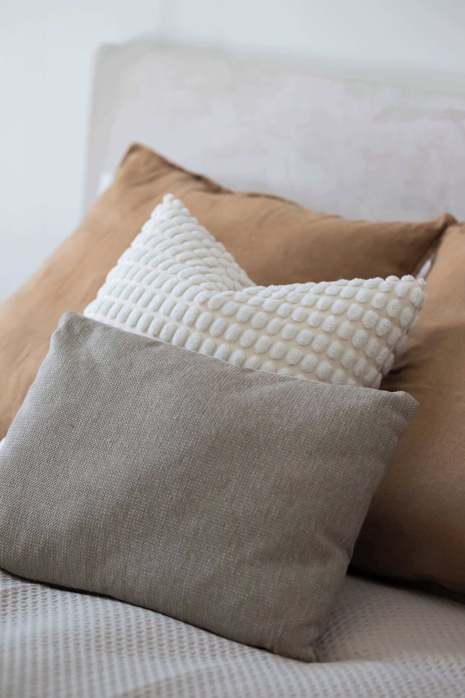 A decorative close-up of cushions and textiles on the bed. The textures add warmth and a sense of comfort.