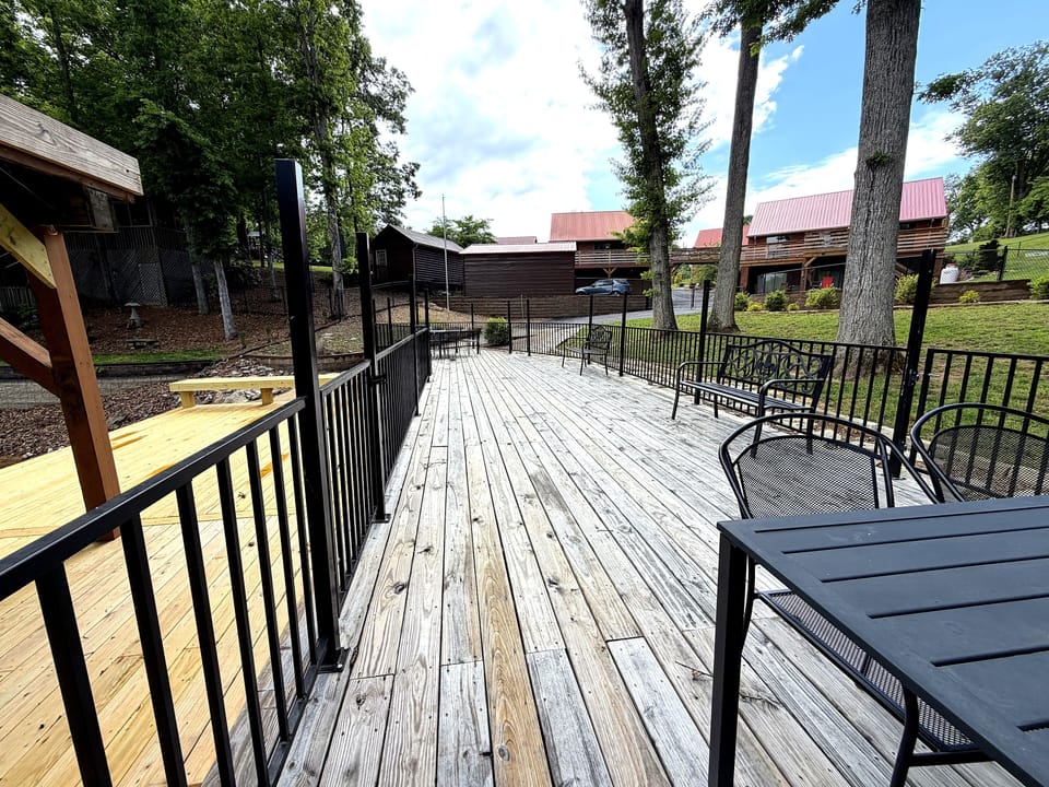 Expansive deck with outdoor dining area and beautiful views of the surrounding cabins and mature trees.