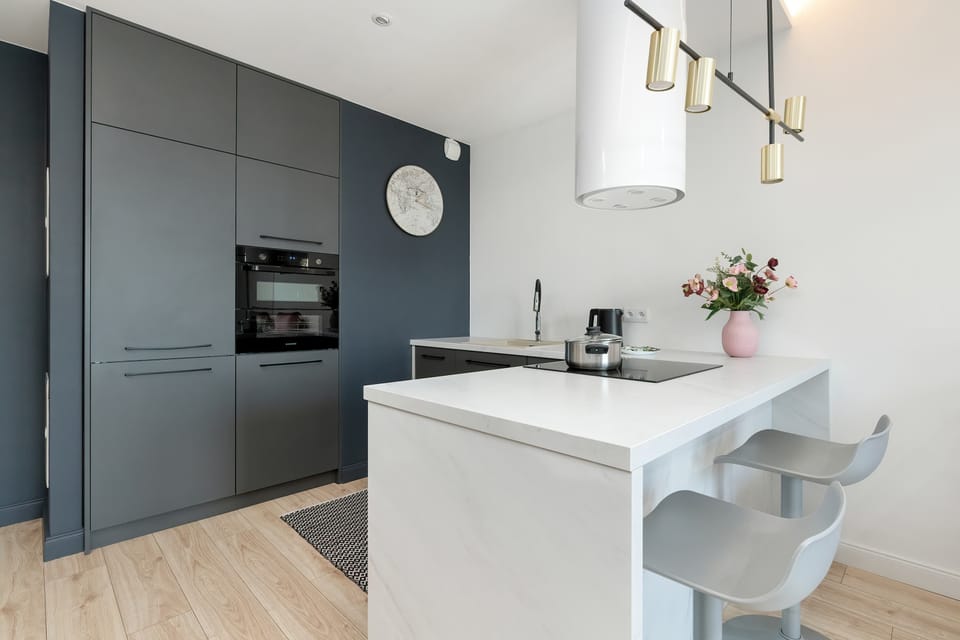 Practical kitchenette with graphite cabinets, built-in appliances and minimalist finishes.