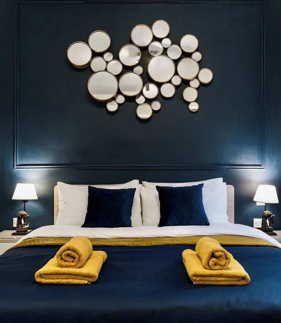 The master bedroom features a king bed, layered textiles, and a refined navy-and-gold palette for a restful night’s sleep.