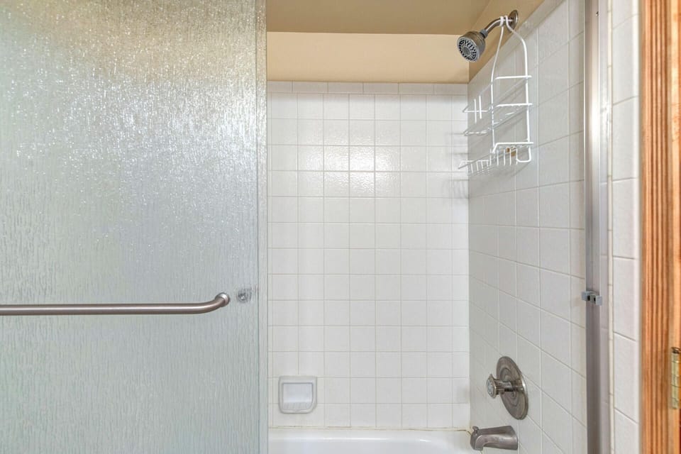 Step into your spotless tiled shower with its refreshing rainfall head and convenient built-in shelf to keep your essentials close at hand.