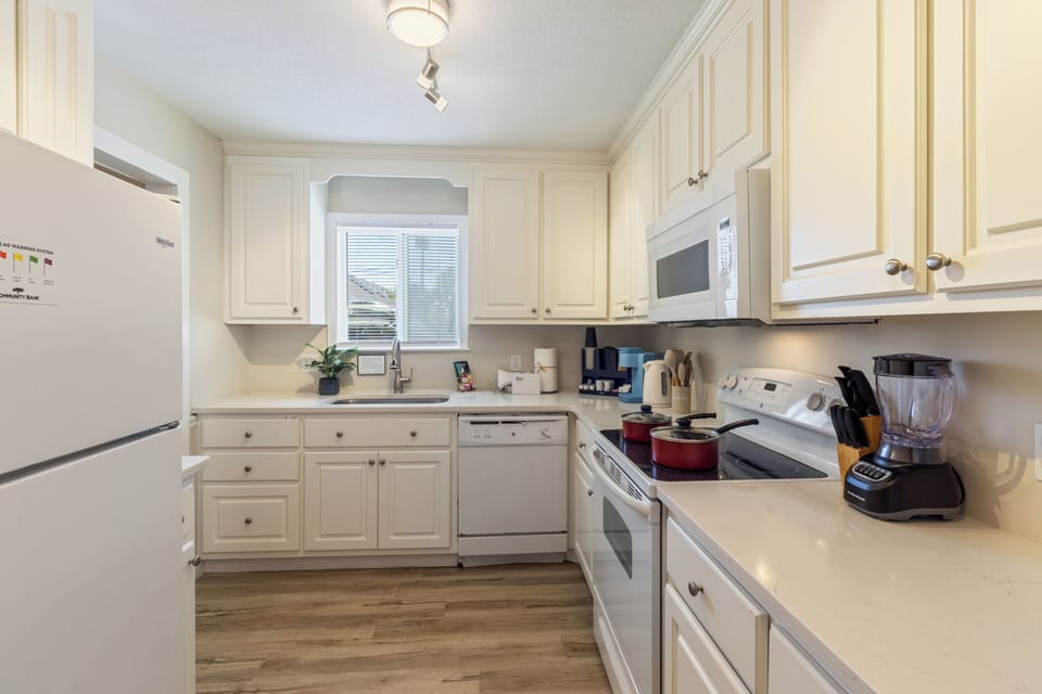 Bright, fully equipped kitchen with white cabinetry, spacious countertops