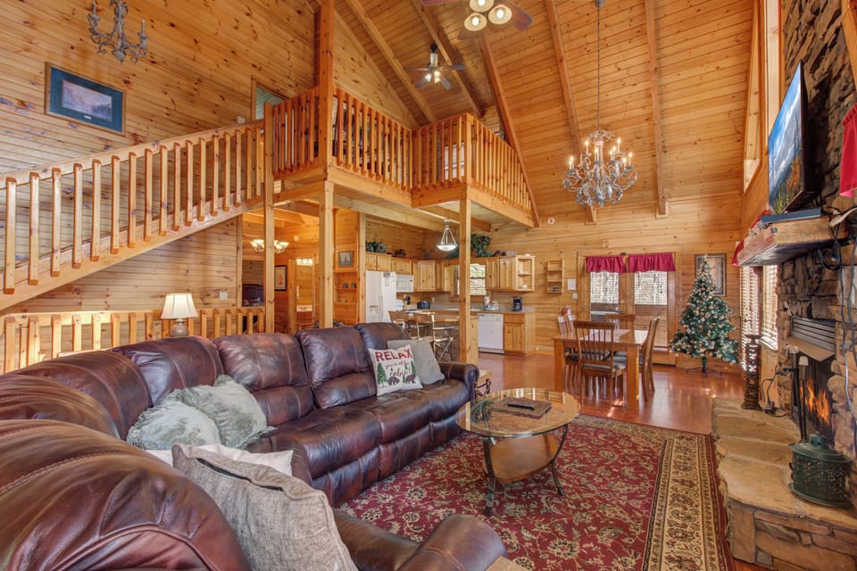 Relax in your spacious cabin's warm living room with vaulted ceilings, leather seating, and a crackling fireplace for cozy mountain evenings.