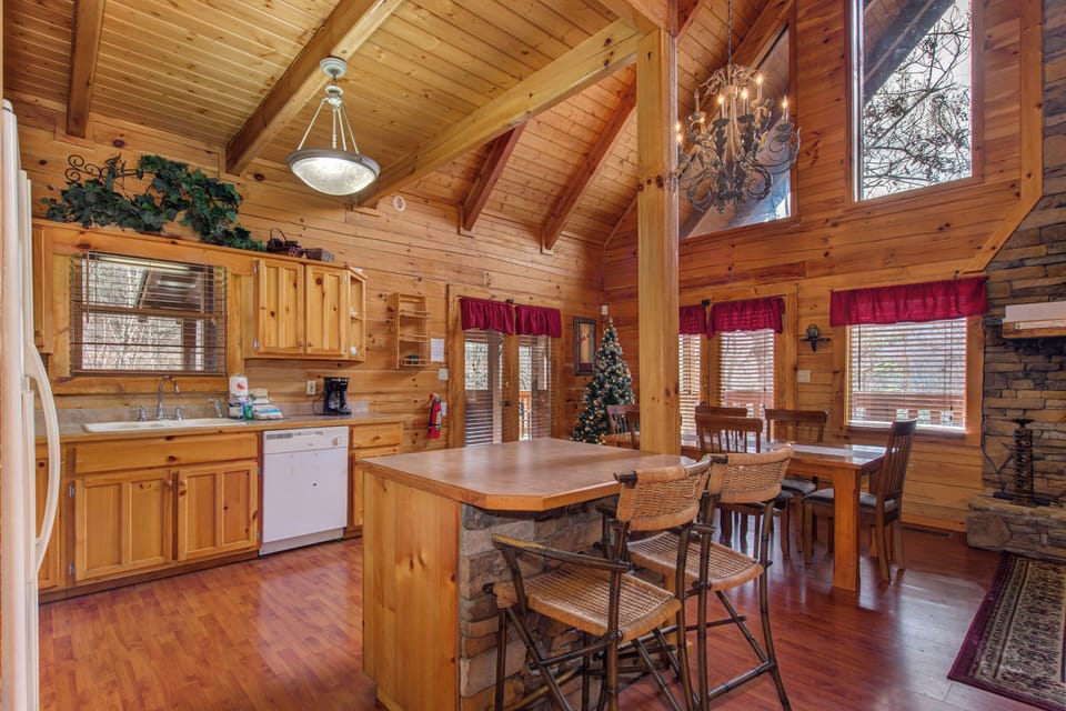 Gather around your rustic kitchen island where warm wood tones and soaring cathedral ceilings create the perfect space for morning coffee.