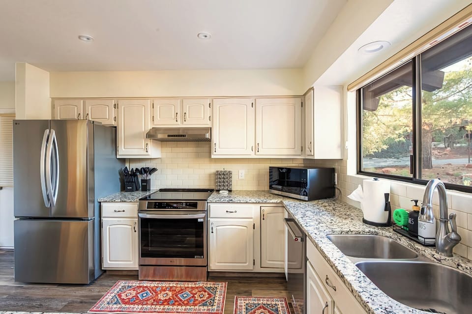 Chef's kitchen with stainless appliances, granite counters, Keurig, and cookware