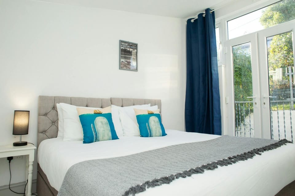 Bed next to French doors, blue curtains and balcony railing