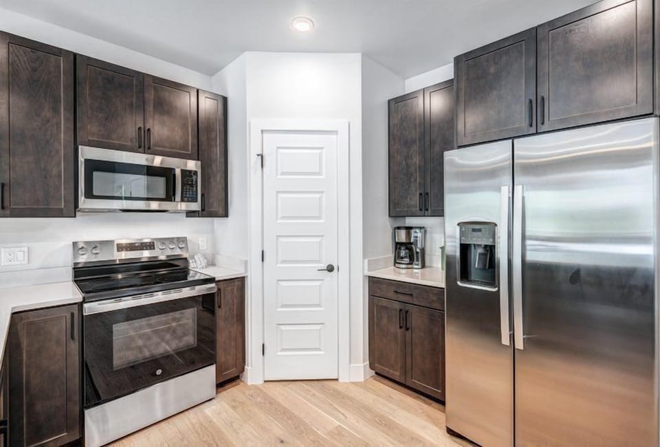 The gourmet kitchen boasts sleek stainless steel appliances and dark cabinetry, creating a sophisticated space for culinary enthusiasts.