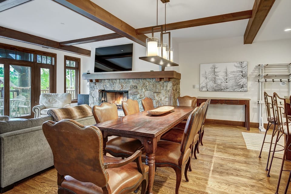 The dining area exudes mountain luxury with its elegant decor, cozy leather seating, and a charming stone fireplace that offers an inviting ambiance.