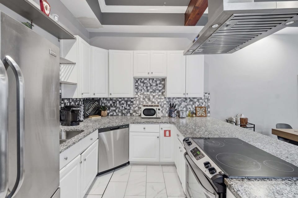 Reverse kitchen view with the cooking peninsula, dishwasher, coffee maker, and wraparound counters.