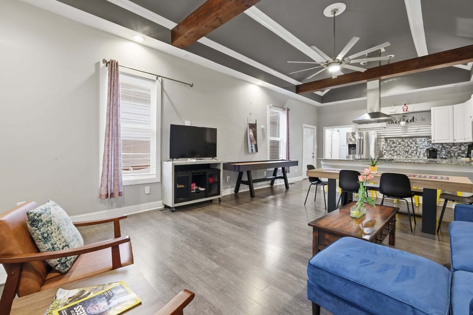 Open living-room view with TV seating, shuffleboard, and the dining and kitchen areas beyond.