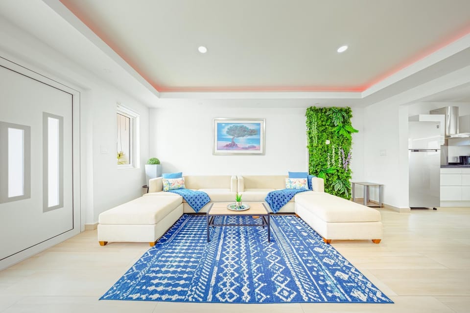 Relax in total comfort on the plush sectional, surrounded by breezy blue accents and a vibrant living wall—perfect for reading, planning adventures, or just unwinding.