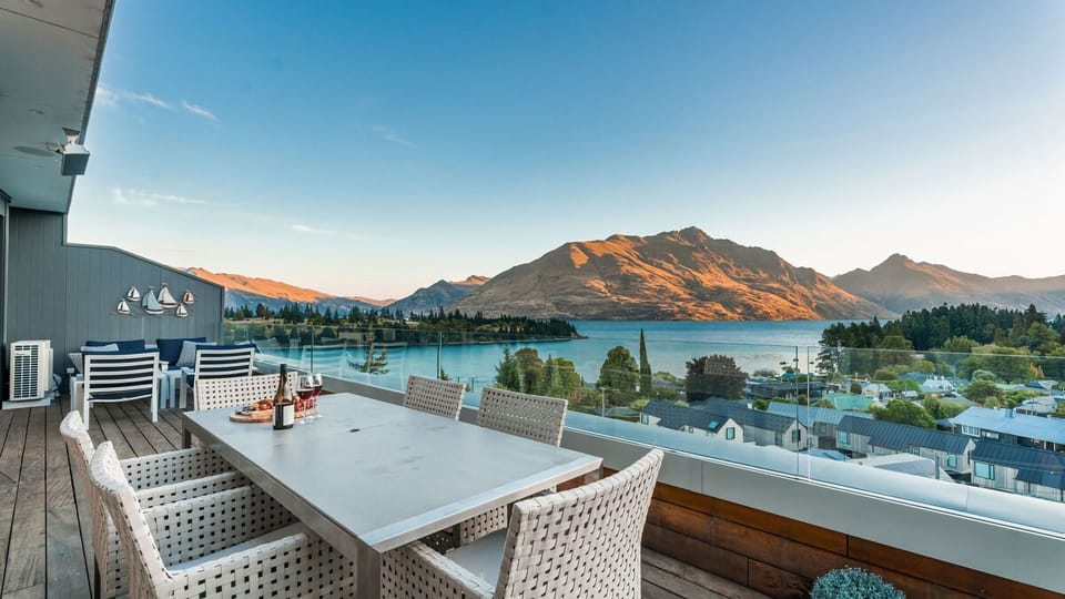 Expansive outdoor balcony with dining table, outdoor heaters, hanging chair, and incredible lake and mountain views. 