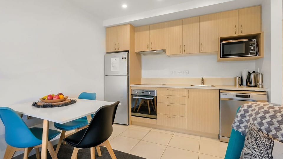 A modern kitchen with full size fridge, oven, stove, microwave and dishwasher. 