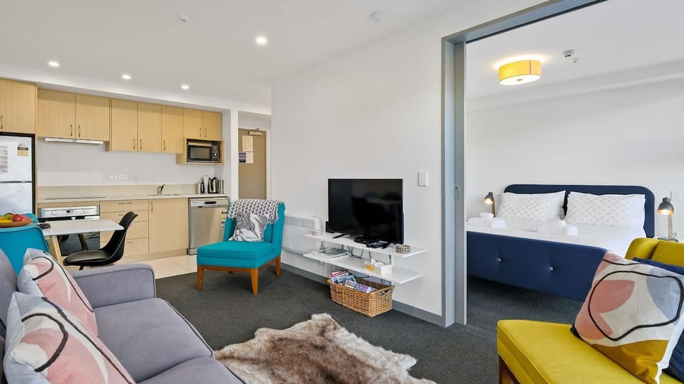 Intimate living area with cosy couch and arm chairs and smart tv.