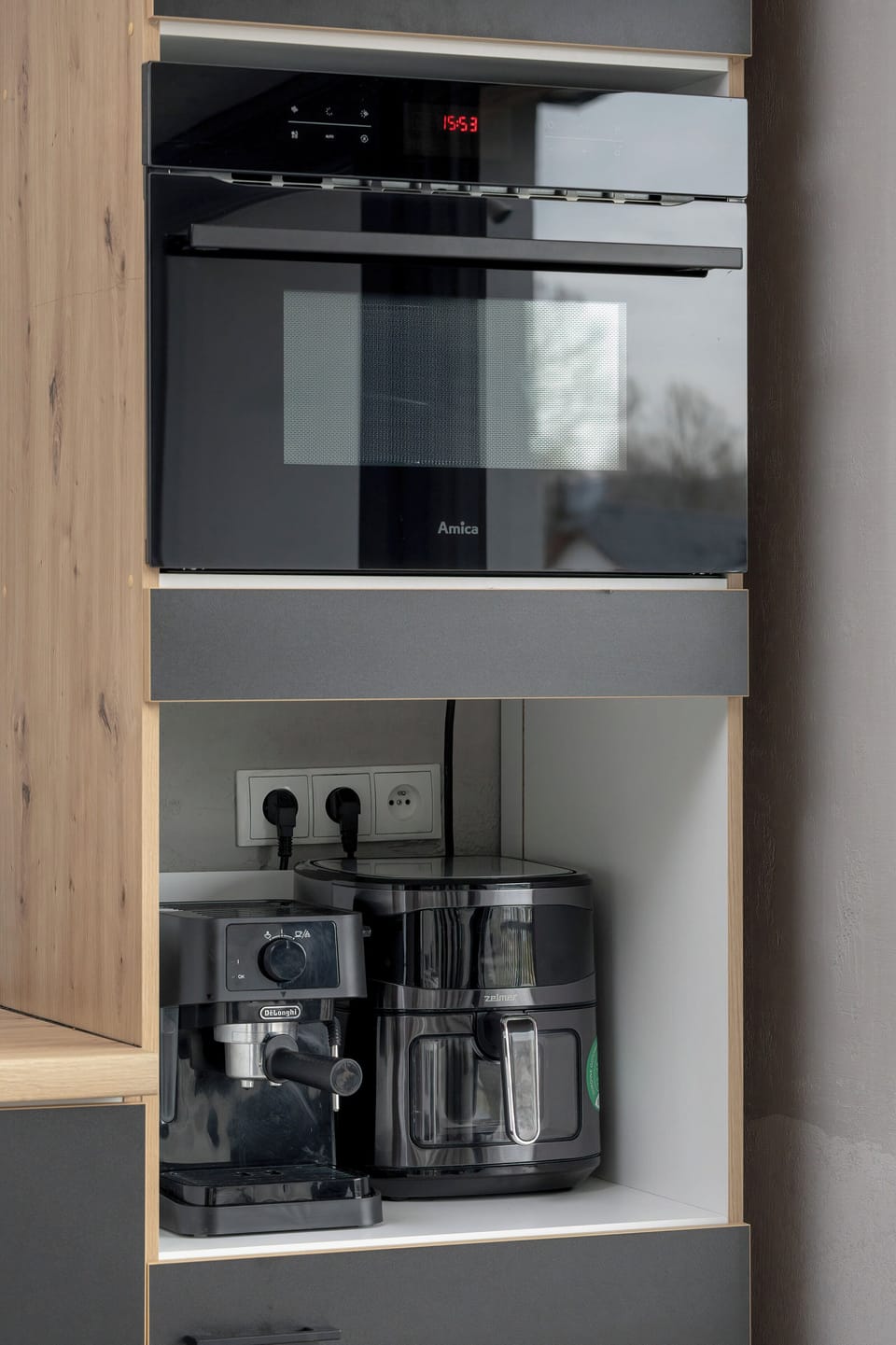 A built-in kitchen cabinet with an oven, coffee machine, and storage compartments. The layout is efficient and sleek.