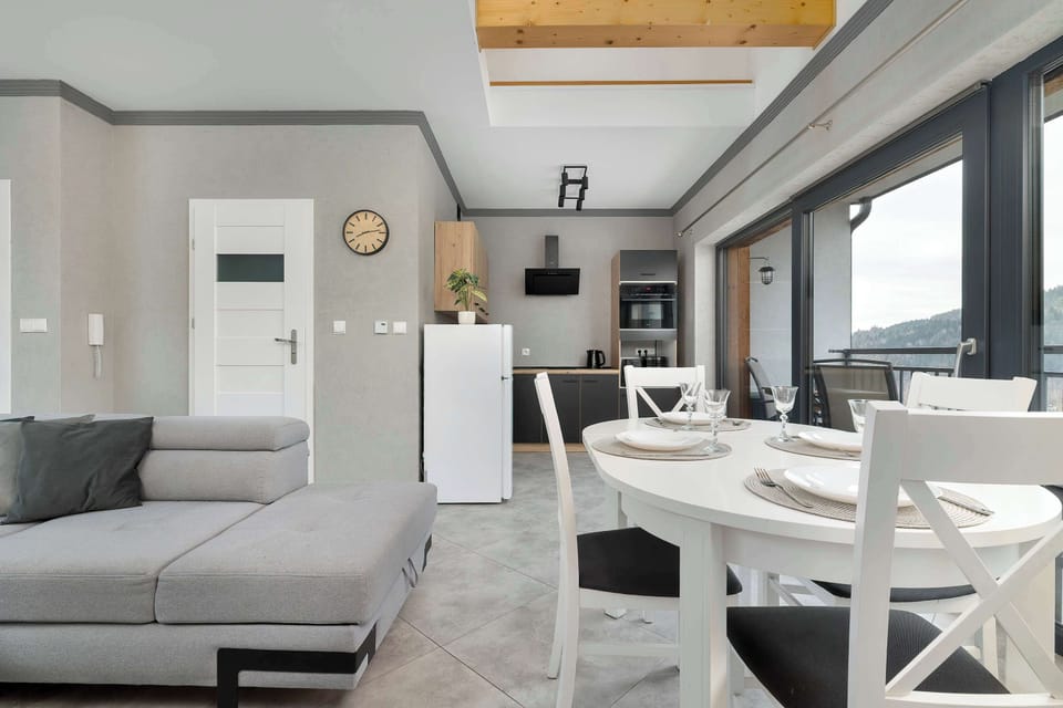 A living and dining area combination with a sofa, table, and open kitchen in the background. The space feels integrated and modern.