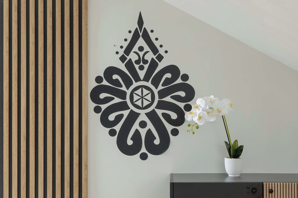 A decorative wall with vertical wooden slats and a black ornamental pattern. A small plant adds a touch of greenery.