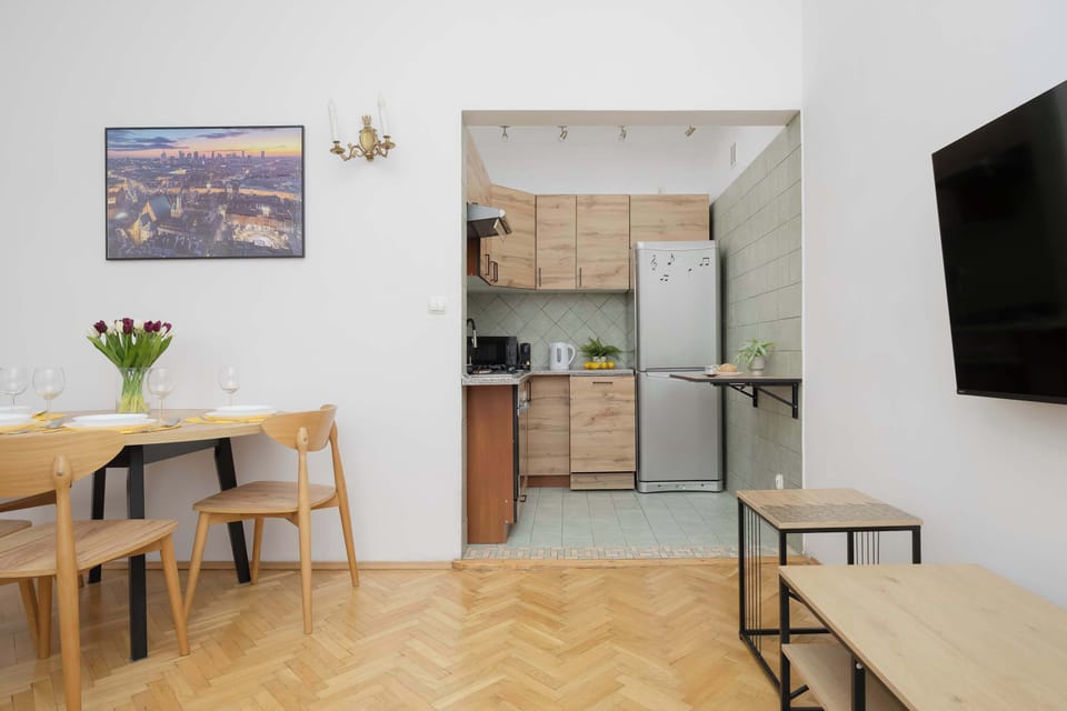 This modern apartment blends functionality with style, featuring a compact alcove kitchen, elegant parquet flooring, and a cozy dining area. 