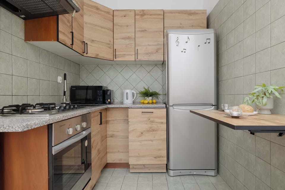 A bright kitchen equipped with a microwave oven, dishwasher, electric kettle, and refrigerator with freezer compartment.