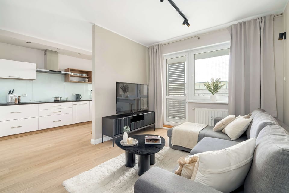 Inviting living room with refined grey seating, soft drapery, and a warm wooden floor.