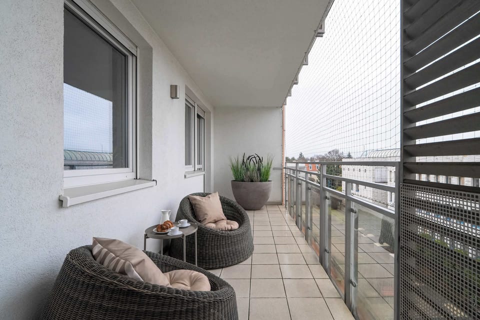 Relaxing balcony spot with seating, modern railing, and open outdoor views.