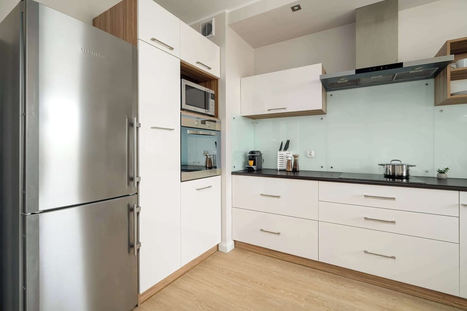 Modern kitchenette with mint-coloured backsplash, smooth cabinetry, and wood accents.