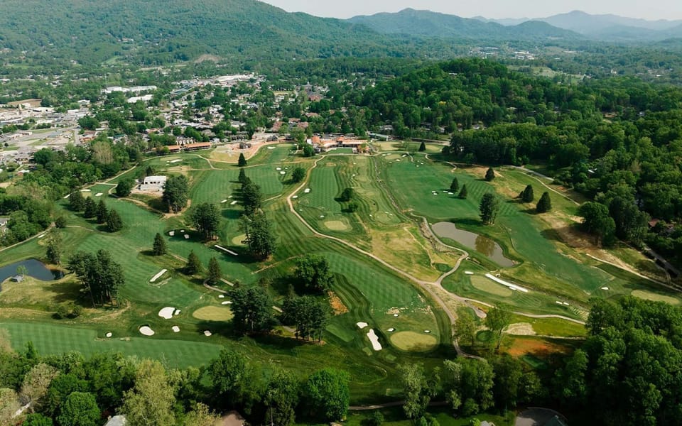 Wide golf course view with clubhouse and town in the distance