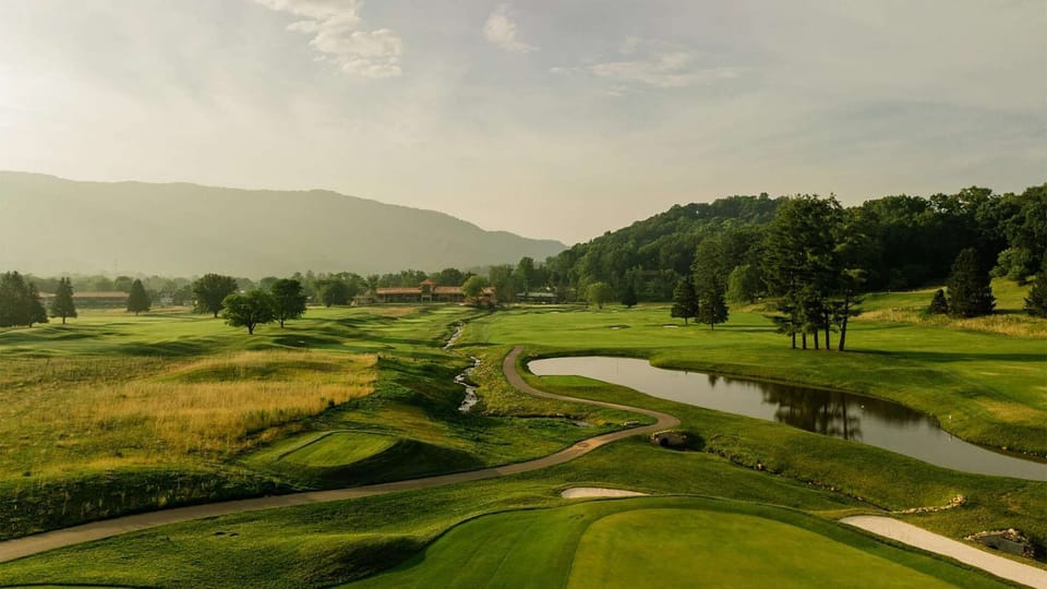 Peaceful course with pond, trees, and mountain backdrop