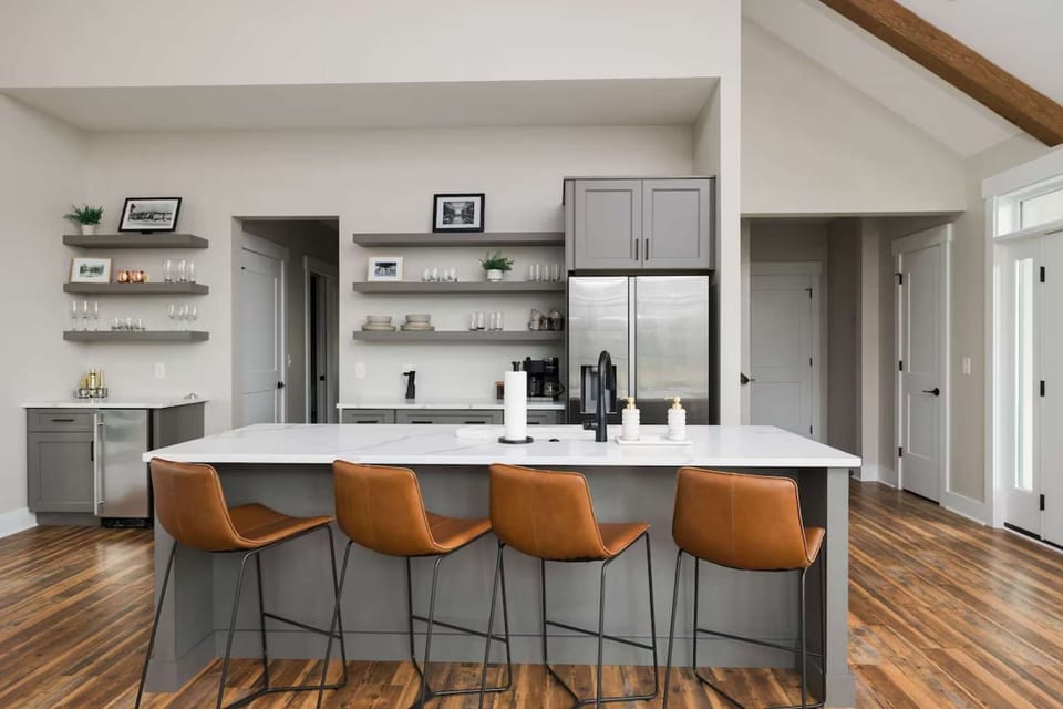 Open kitchen with shelves, wood floors, and bar stools