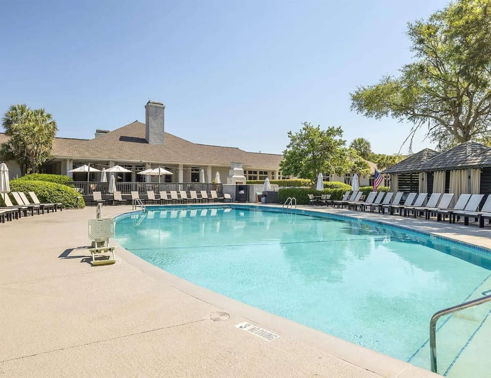 Spacious pool area lined with loungers and shaded cabanas