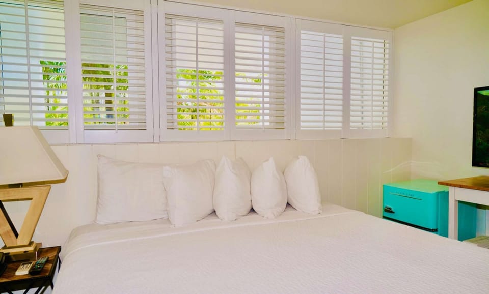 Bright room with white shutters and a mint fridge by the bed
