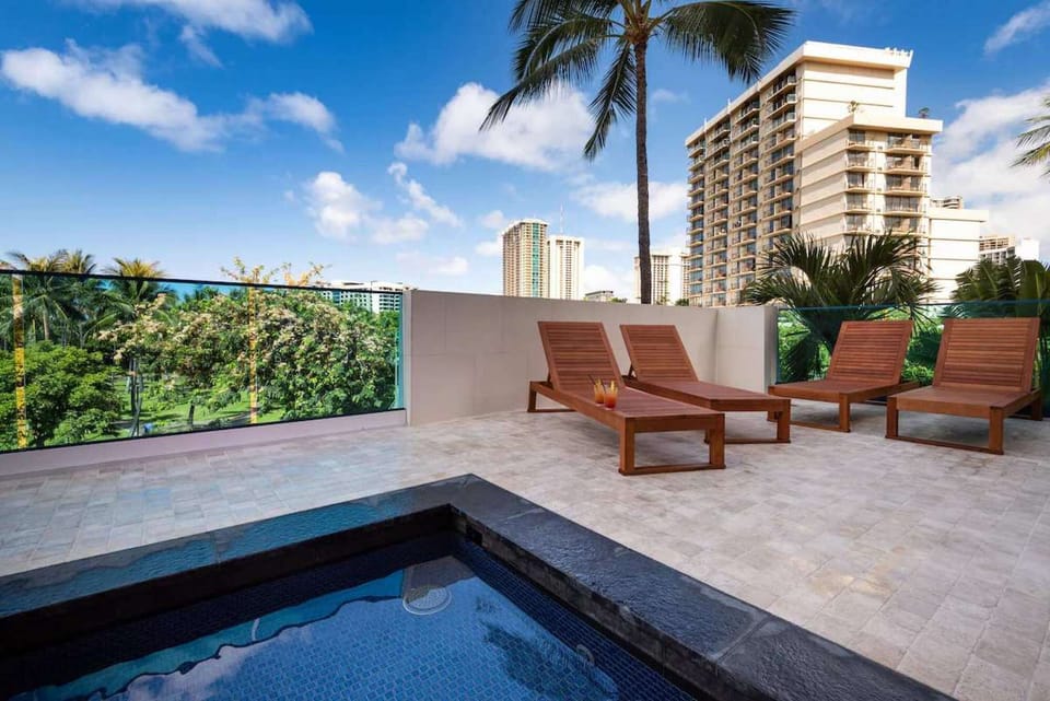 Wooden loungers set beside the pool with city views
