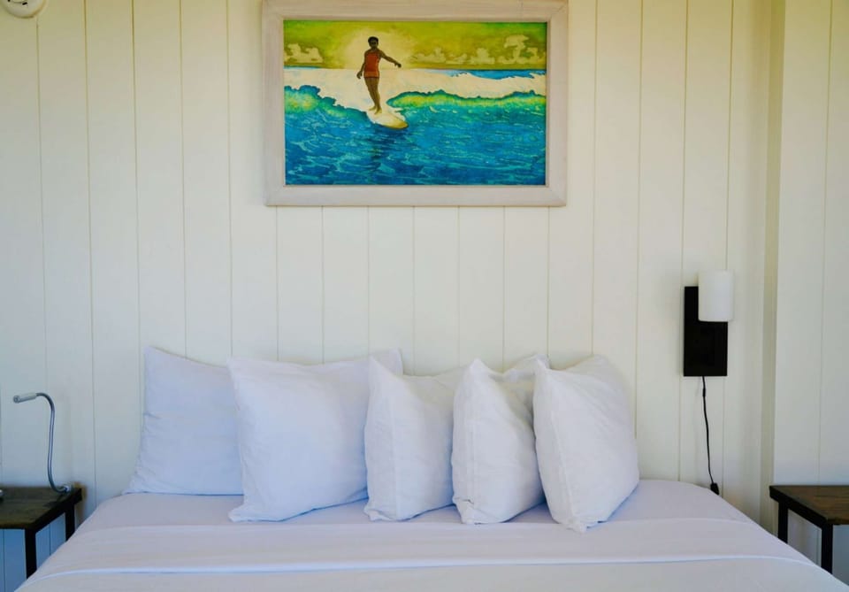 Bright room with a comfy bed and a surfer painting above it