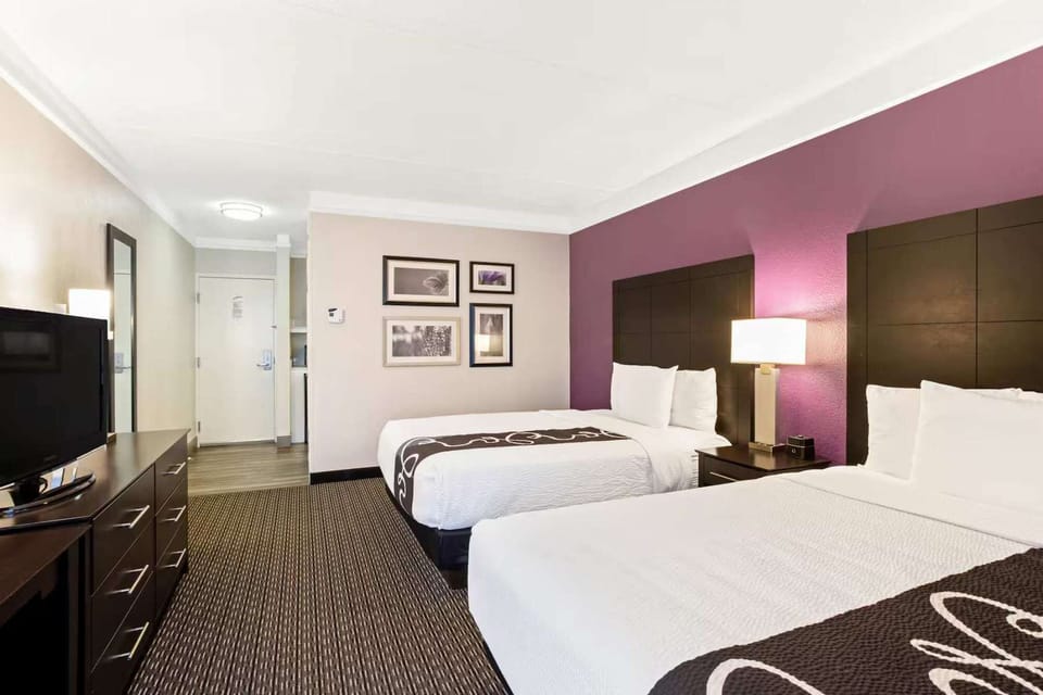 Double queen room with TV, artwork, and calm lighting