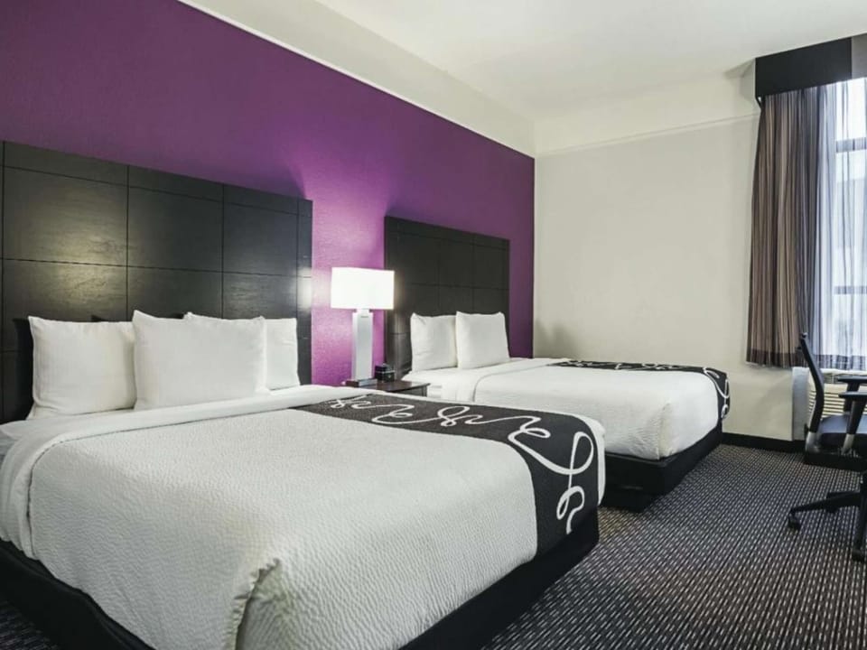 Two queen beds with purple accent wall and bedside lamps