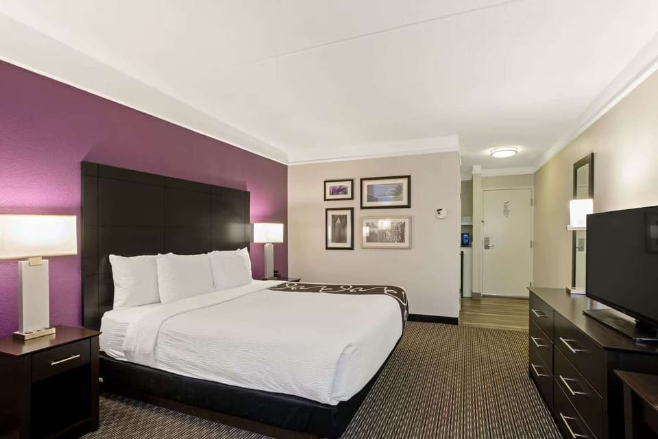 Spacious king room with desk, TV, bright decor, and framed art