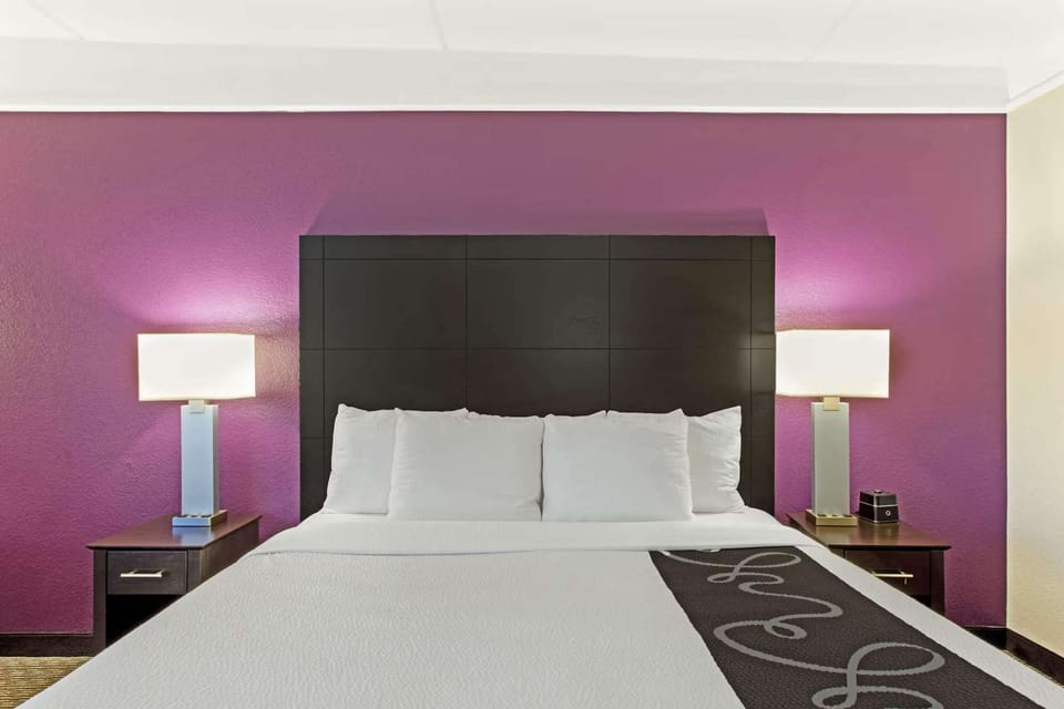 King bed with bright purple wall and soft lamps on each side