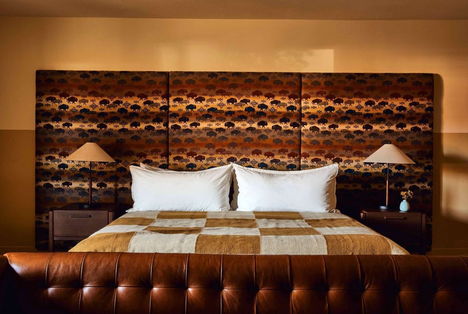 Wide bed view with twin lamps, headboard, and leather bench