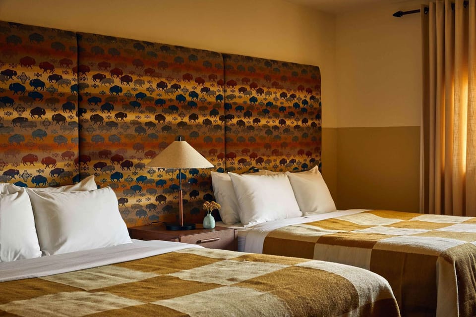 Two beds with lamp, nightstand, and patterned headboard