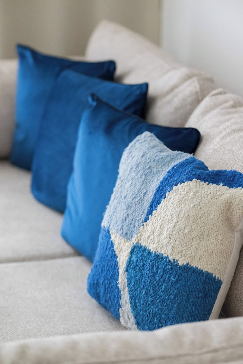 A close-up of a sofa with decorative blue and white cushions. The detail highlights the apartment’s stylish interior touches.