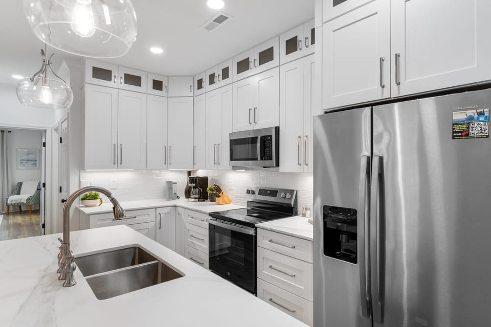 Your modern kitchen awaits with sleek white cabinets and stainless steel appliances, perfect for preparing memorable meals during your stay.