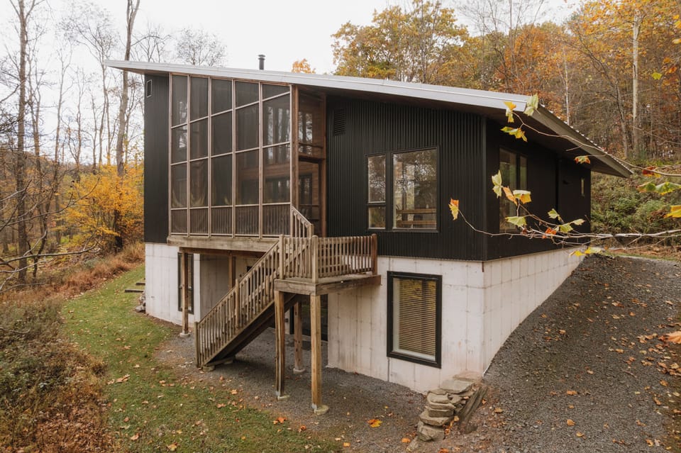 Exterior of the back of the house with screened porch overlooking the stream.