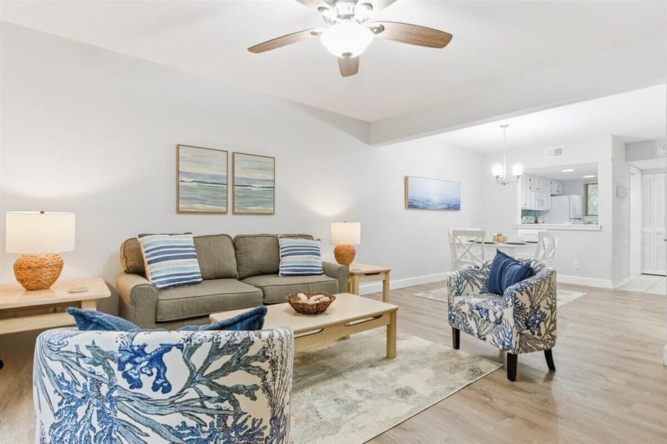 Bright coastal living room with balcony views, smart TV, and comfy seating.