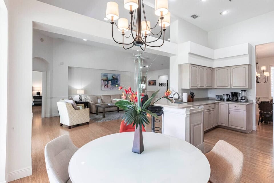 A spacious open living room with vaulted ceilings, warm hardwood floors, and abundant natural light.