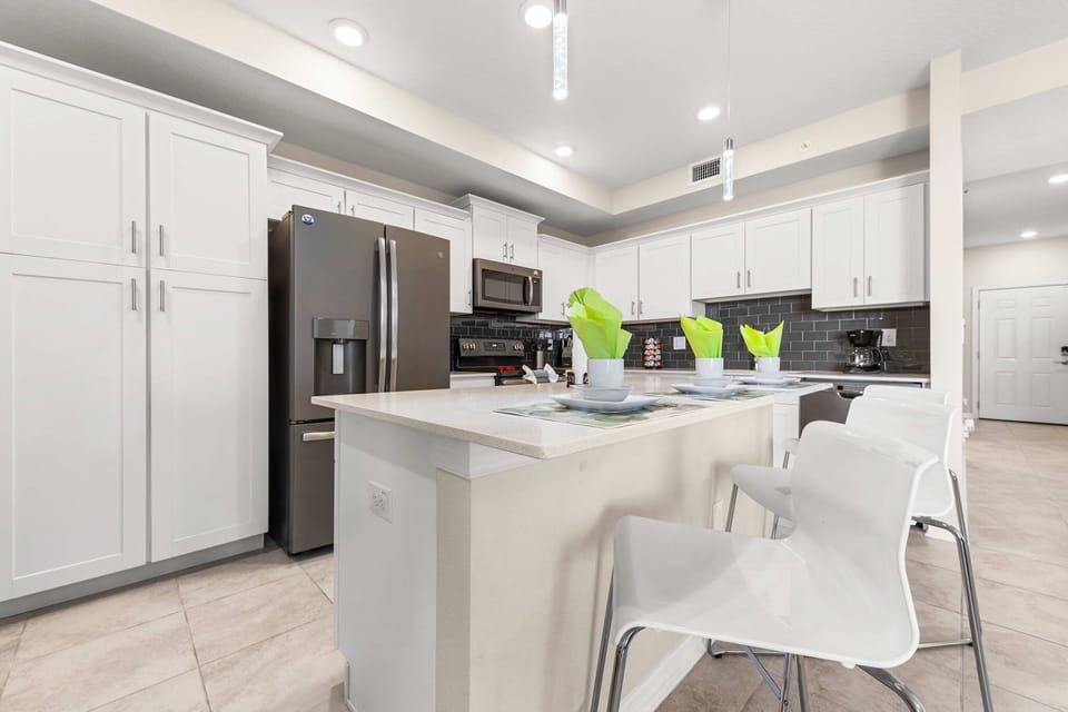 Open-concept kitchen with a bright island breakfast bar for 4, pendant lighting, and clean white cabinetry-perfect for casual bites and conversation.