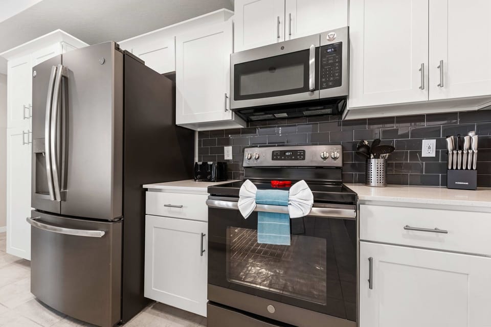 Chef-ready kitchen with sleek stainless appliances, glossy subway tile, and crisp white shaker cabinets-modern and spotless.
