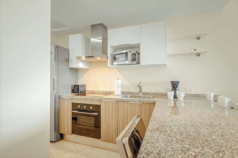 Fully equipped modern kitchen with stainless appliances and bar seating, ideal for cooking and gathering together.