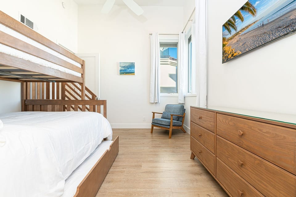 This upstairs bunk room pairs warm wood finishes with coastal light, creating a welcoming space for rest and relaxation
                