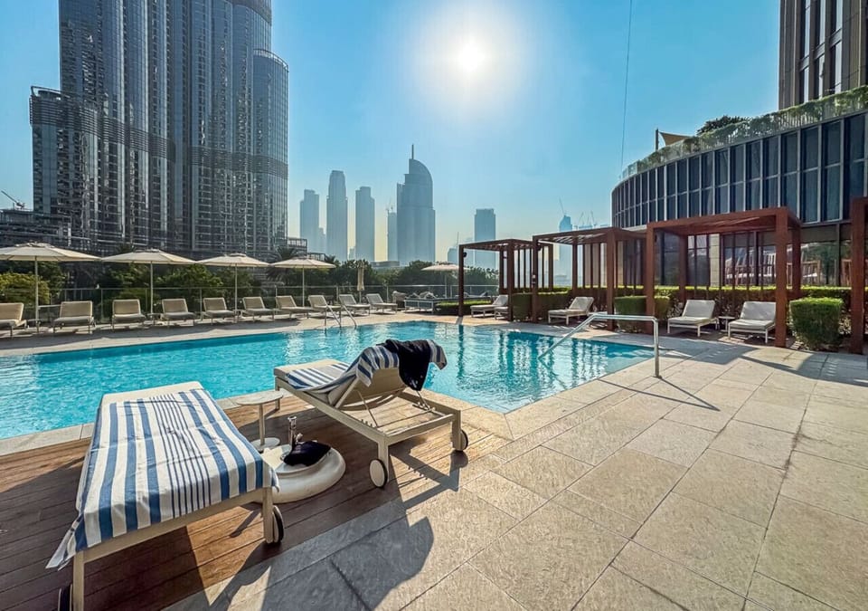 Serene resort-style pool deck with premium stone and warm wood finishes.