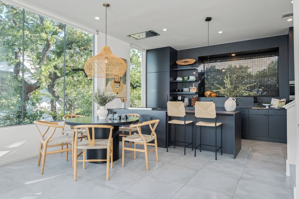 Dining area adjacent to the kitchen, highlighting the black cabinetry and light flooring.